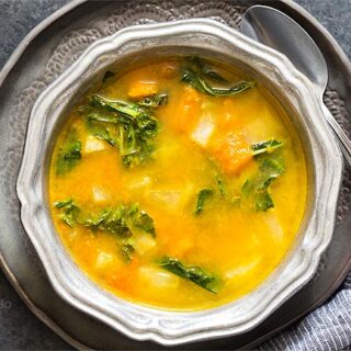 Kohlrabi Soup with Kohlrabi Greens in a silver ridged bowl on a dark gray plate