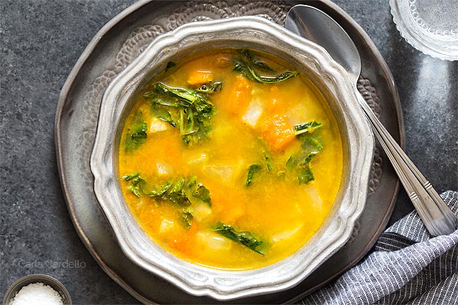 Kohlrabi Soup with Kohlrabi Greens in a silver ridged bowl on a dark gray plate