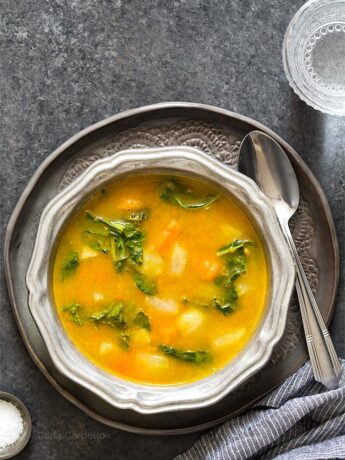 Kohlrabi Soup with Kohlrabi Greens in a silver ridged bowl on a dark gray plate