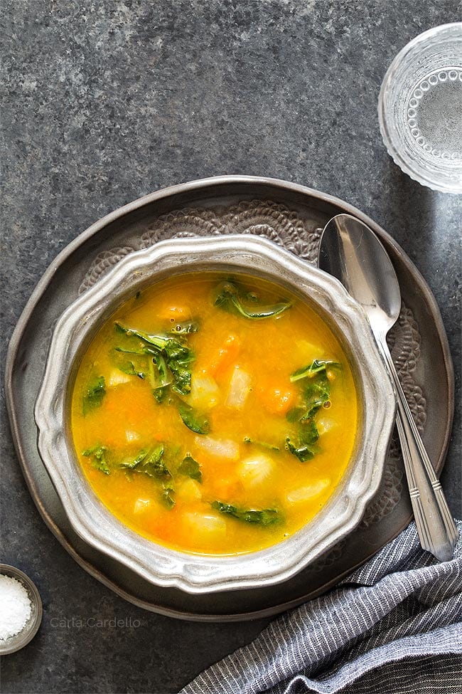 Kohlrabi Soup with Kohlrabi Greens in a silver ridged bowl on a dark gray plate