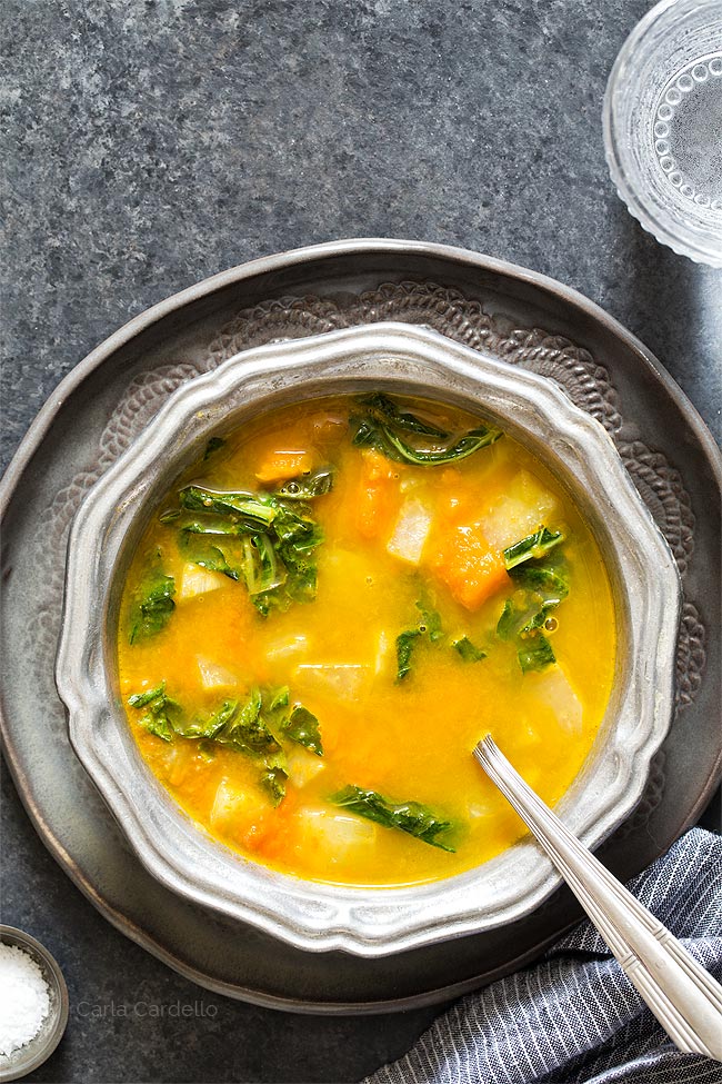 Kohlrabi Soup with Kohlrabi Greens in a silver ridged bowl on a dark gray plate