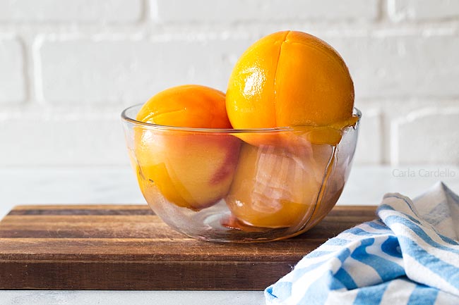 Glass bowl with 3 peeled peaches