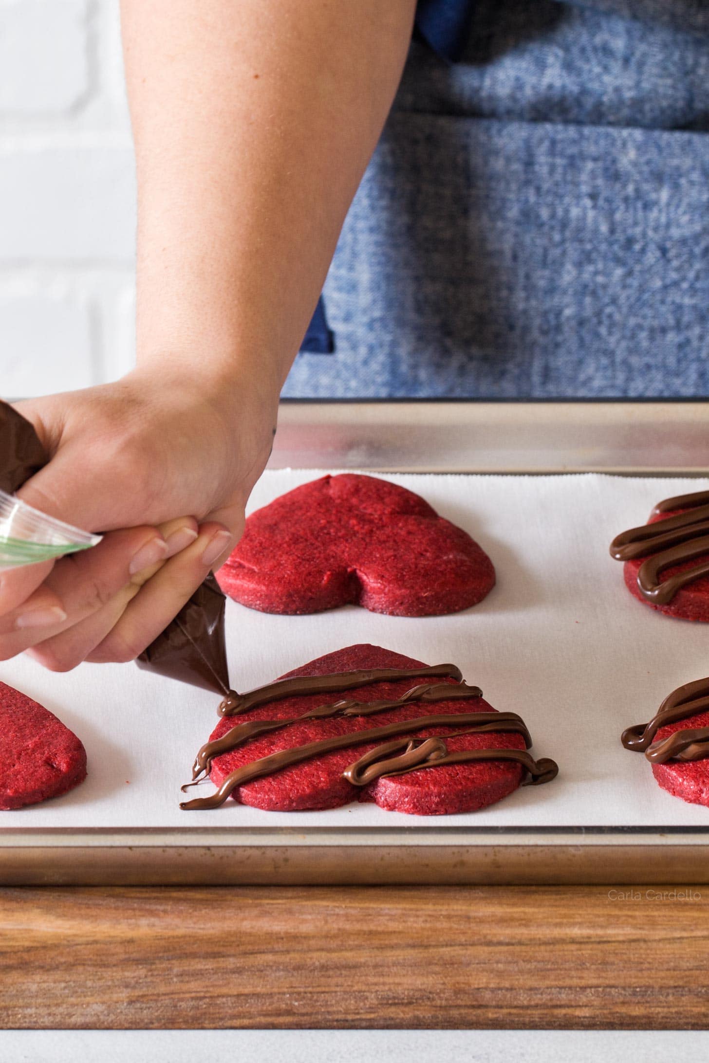 Decorating red velvet sugar cookies with chocolate drizzle