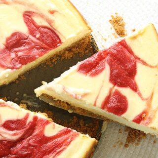 A slice of strawberry cheesecake being removed with a cake cutter