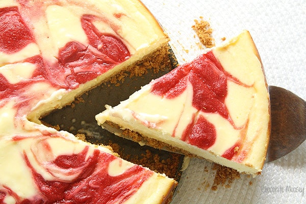 A slice of strawberry cheesecake being removed with a cake cutter