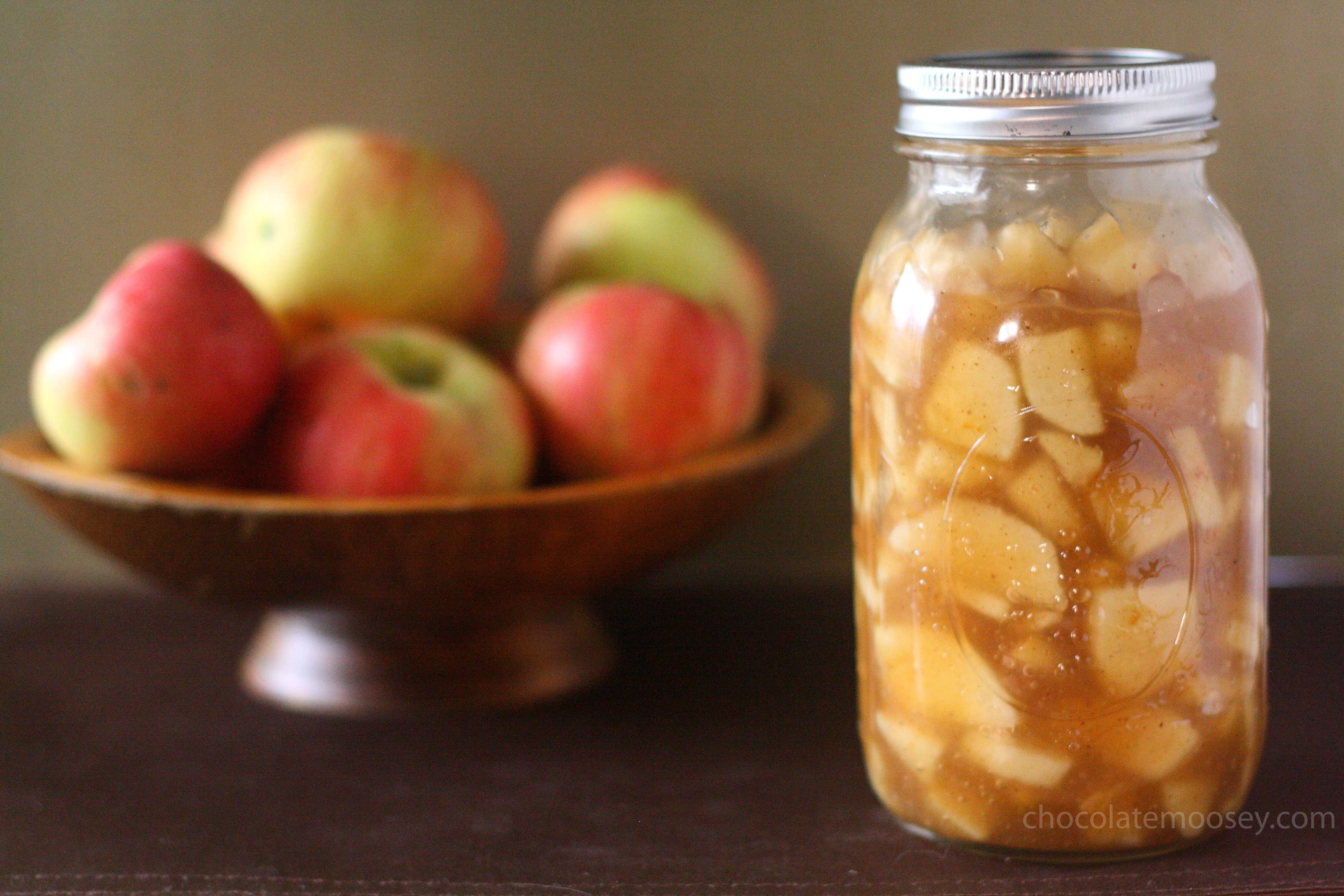 Jar of apple pie filling with bowl of apples