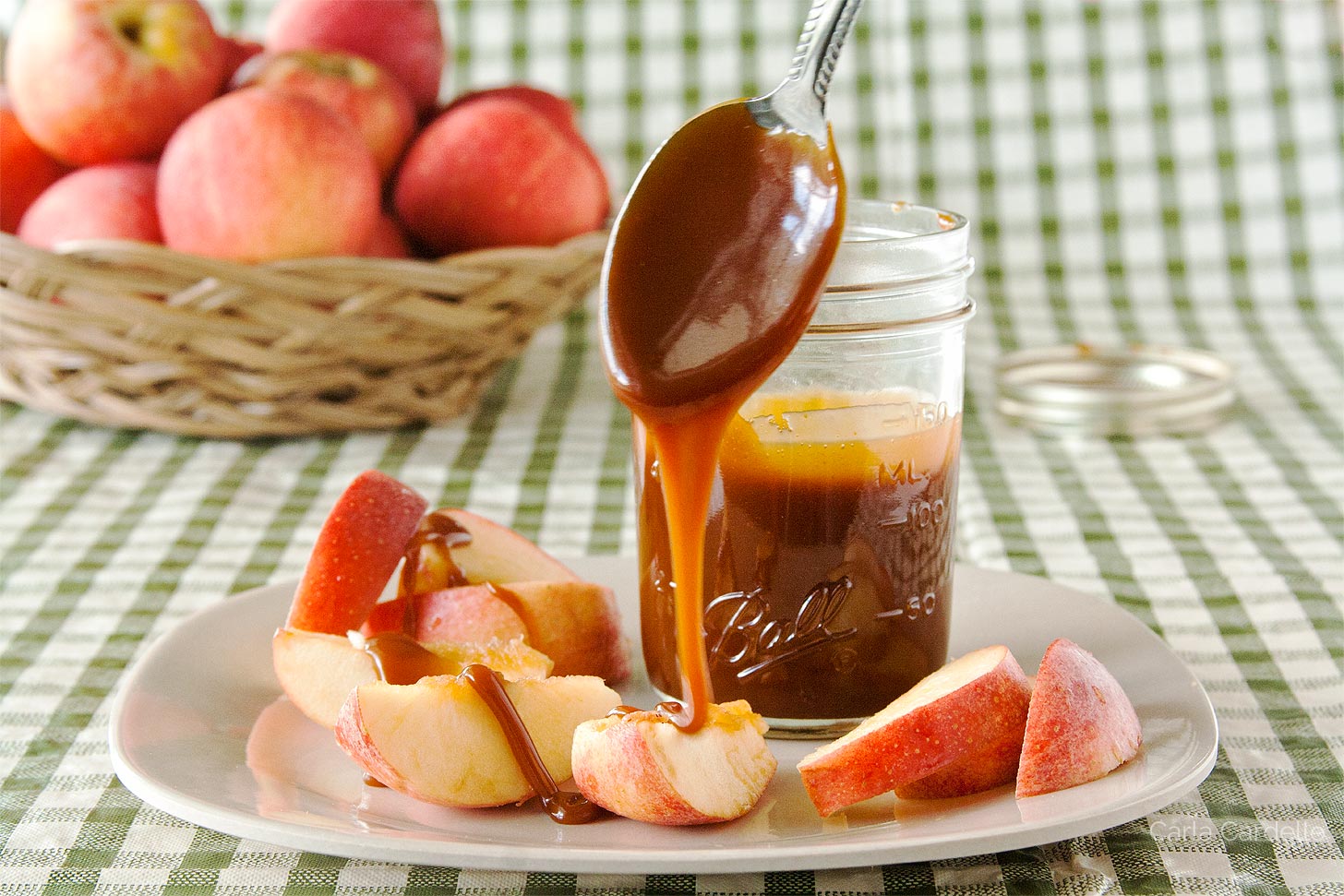 Caramel sauce dripping off spoon onto apple slices