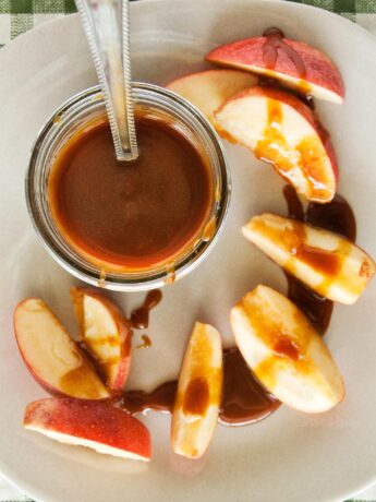 Jar of caramel sauce on plate with apple slices