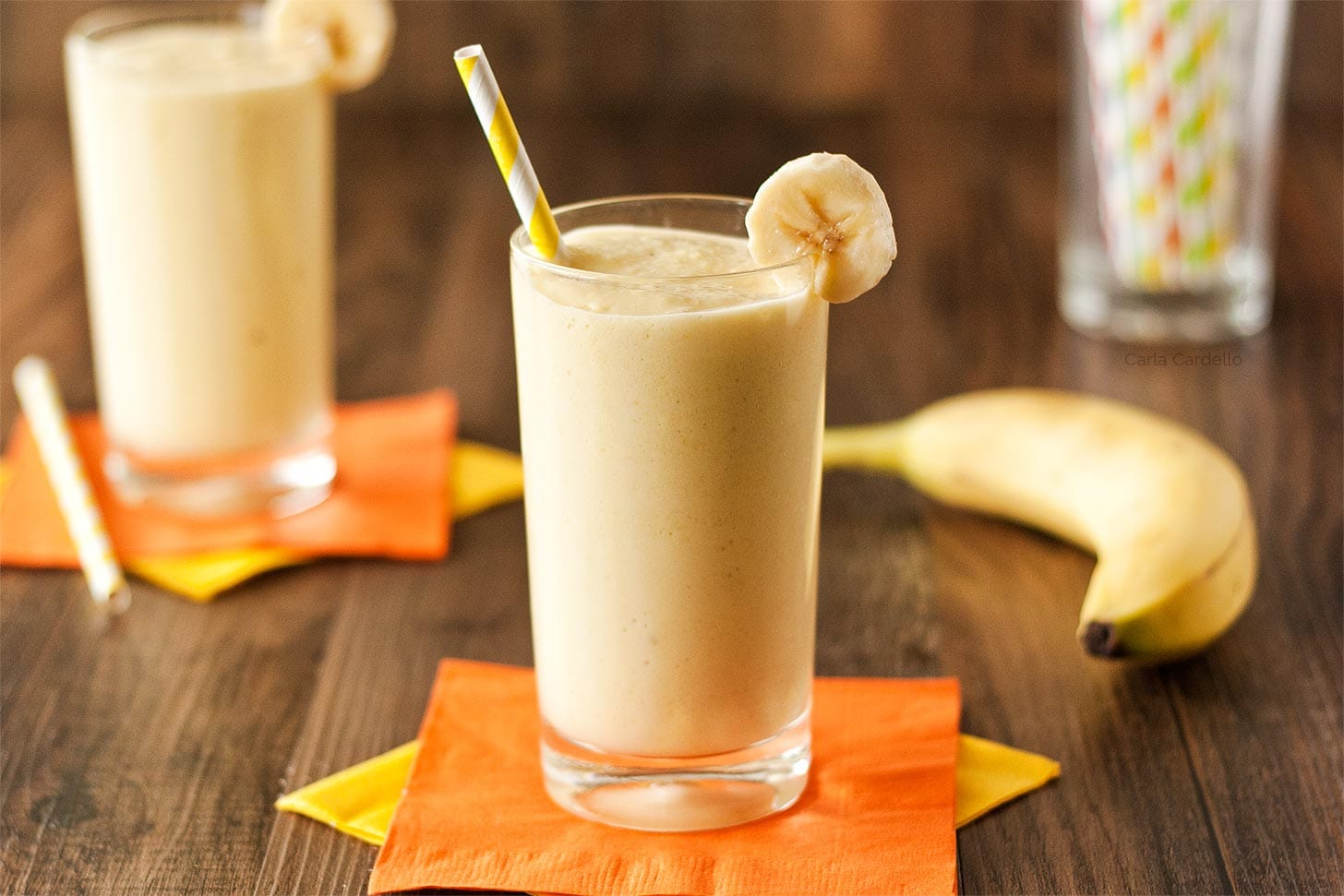 Two glasses of mango banana smoothie with straws