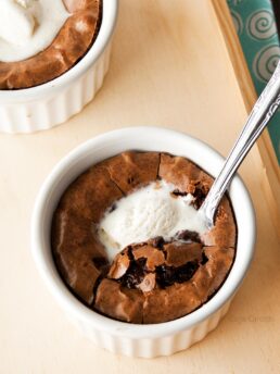 Brownie in a white ramekin with vanilla ice cream on top