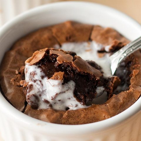 Close up of brownie in white ramekin with spoon in middle