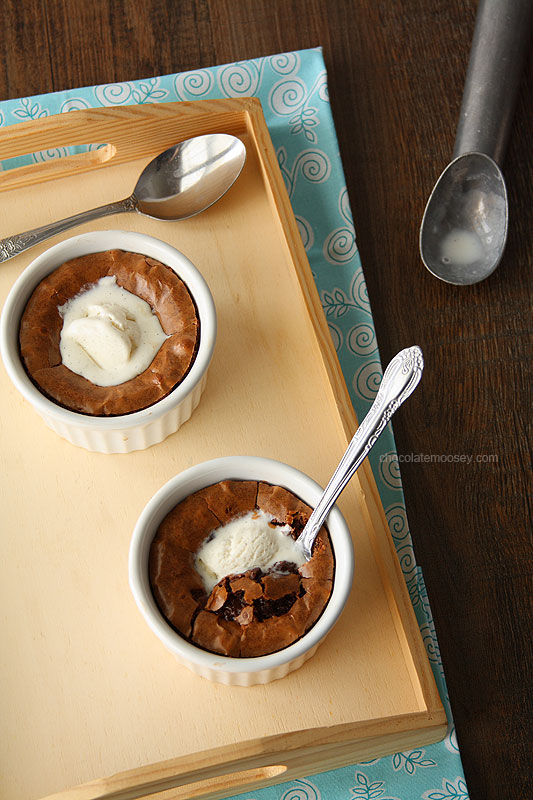 Two brownies in white ramekins on a wooden tray