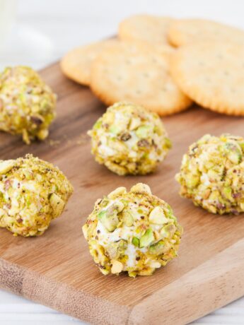 Goat cheese balls with pistachio and bacon on a cutting board