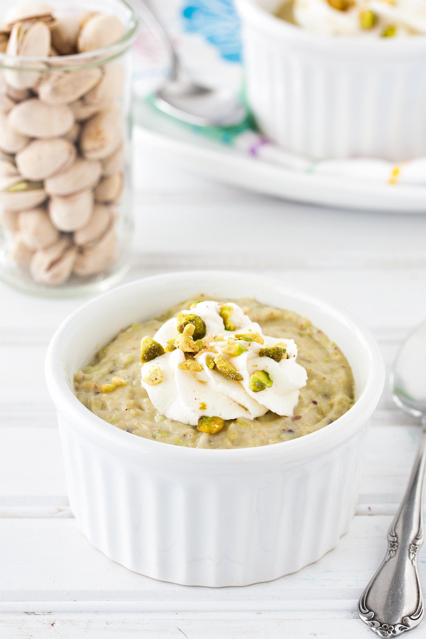 Homemade pistachio pudding in a white ramekin with spoon