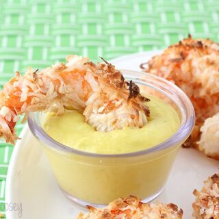 Baked Coconut Shrimp being dipped into mango yogurt sauce