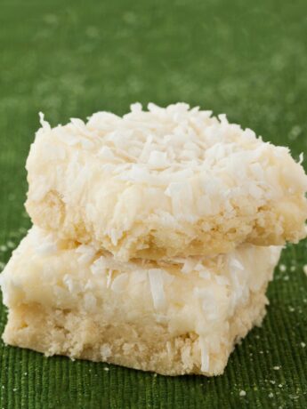 Coconut Cookie Bars stacked on top of each other with green background