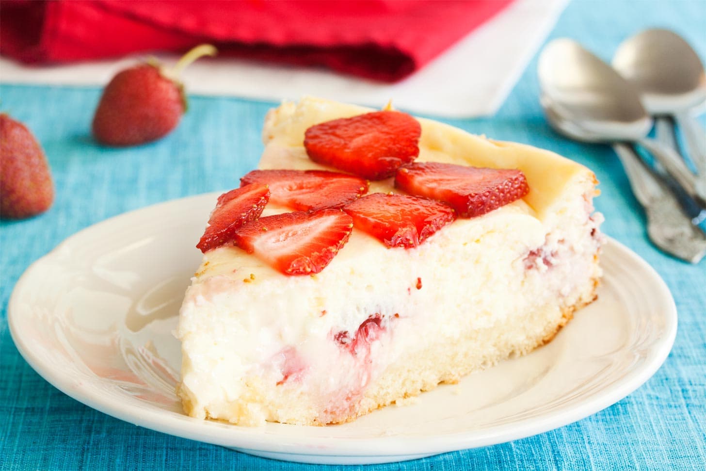 Slice of strawberry shortcake cheesecake on white plate