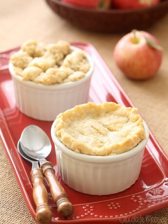Two mini apple pies in ramekins on a red plate