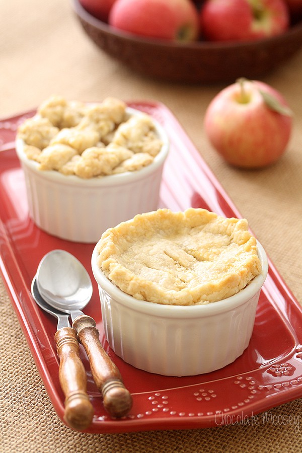 Two mini apple pies in ramekins on a red plate