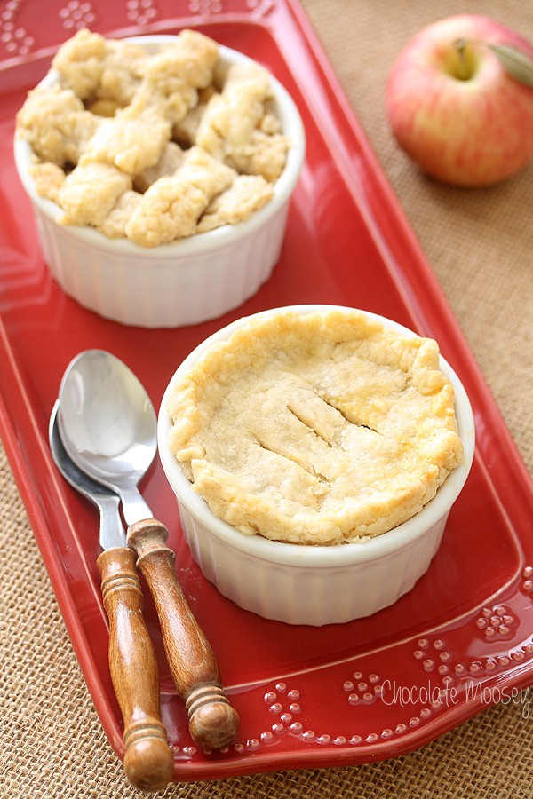 Two mini apple pies in ramekins on a red plate