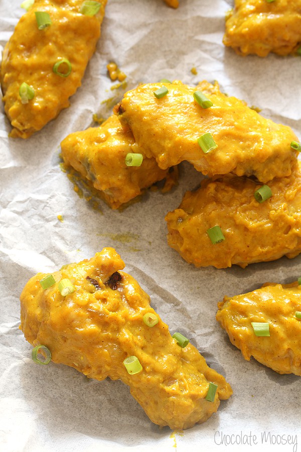 Baking tray lined with parchment paper with curry chicken wings on top