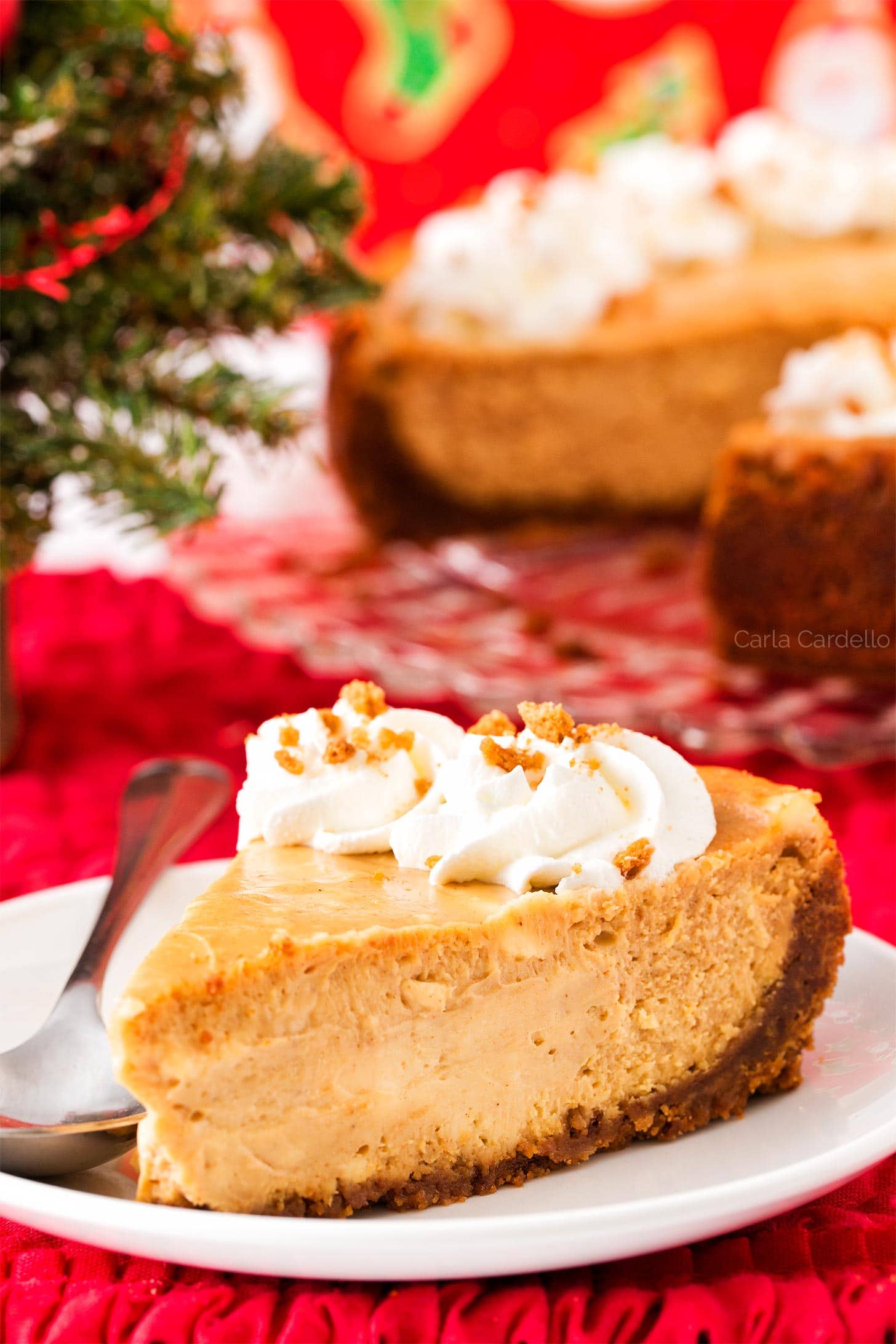Slice of Gingerbread Cheesecake on white plate with Christmas background