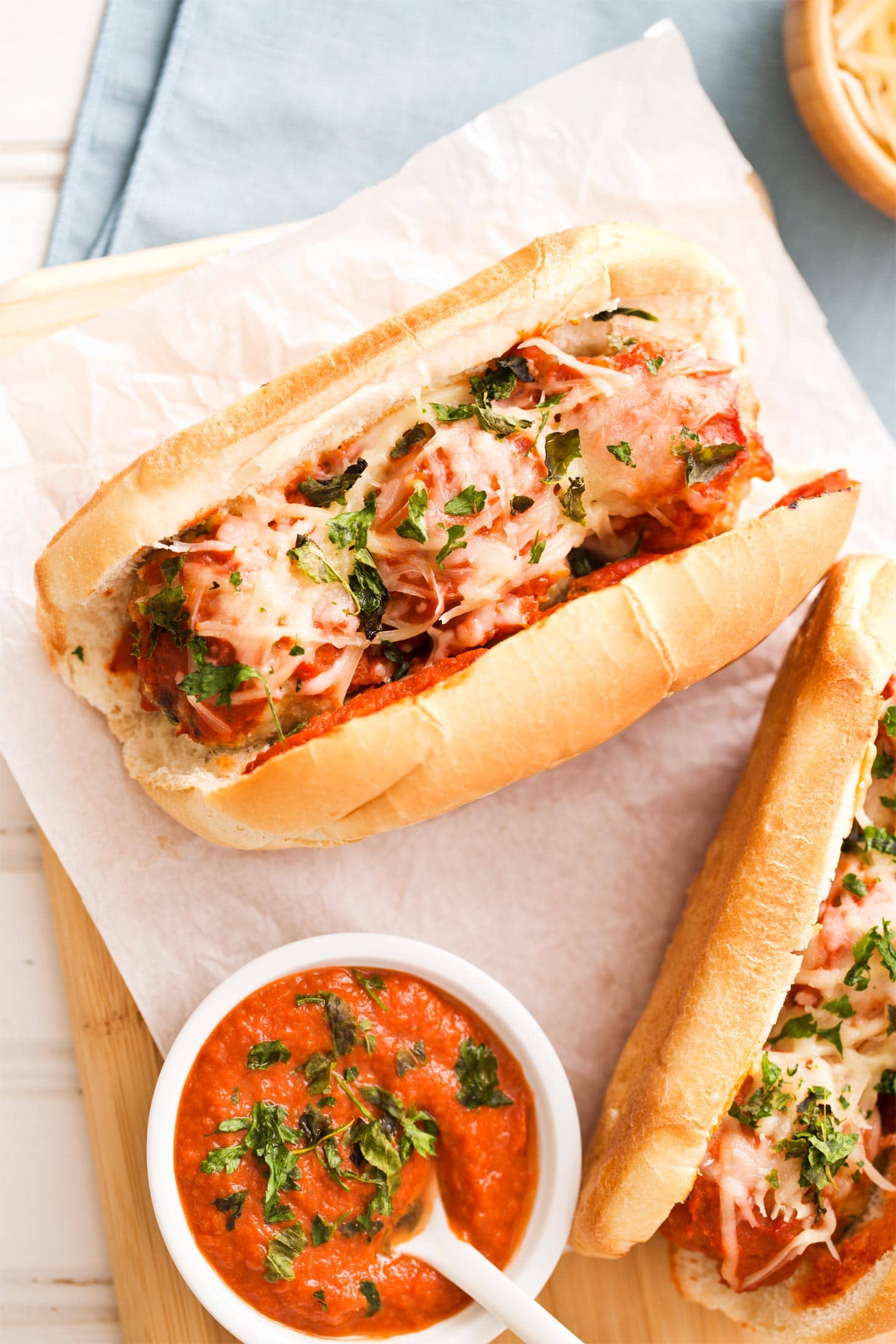 Meatball parmesan sandwiches with sauce on cutting board