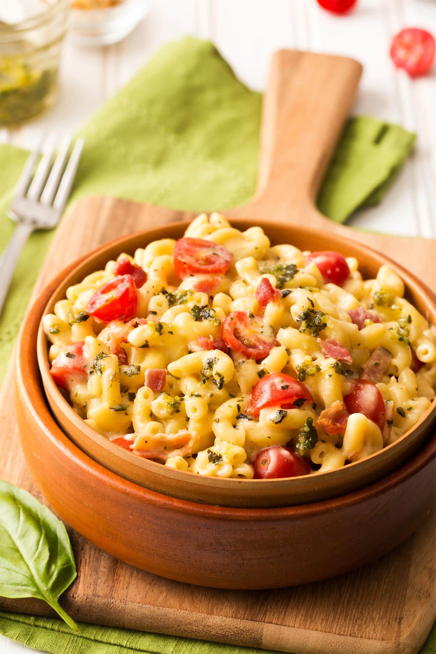 Pesto mac and cheese with bacon served in a brown bowl