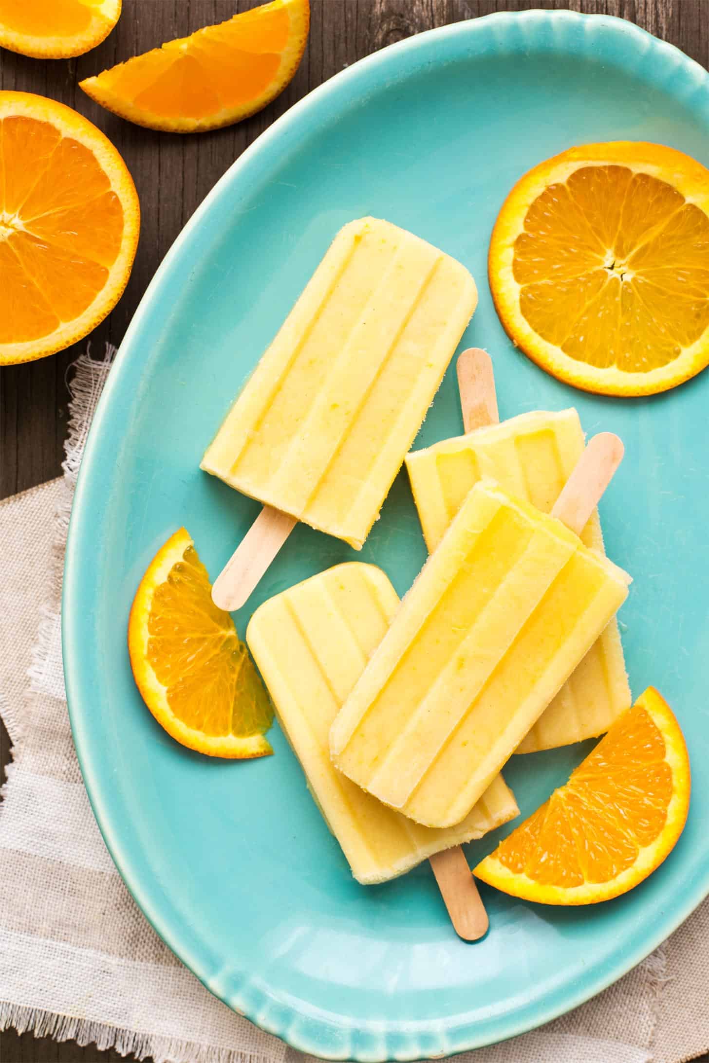 Orange creamsicles stacked on turquoise plate