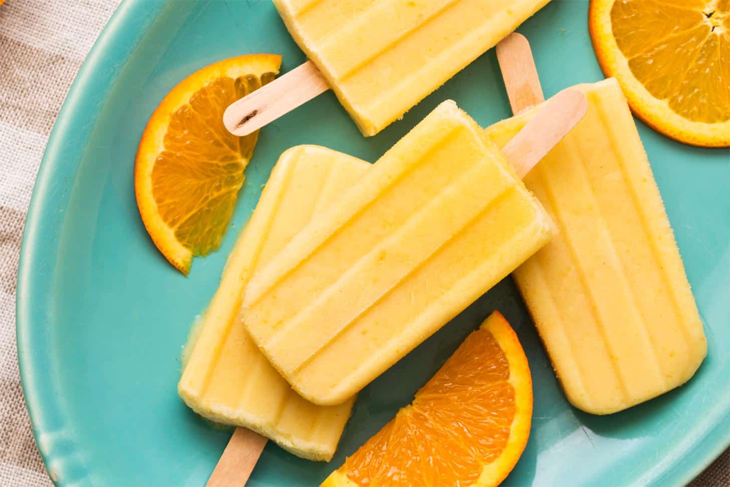Orange cream popsicles on turquoise plate