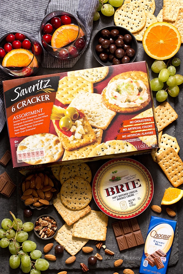 The easiest snack you can make for entertaining holiday guests - Cranberry Baked Brie served on a festive cheese board with crackers and fruit. Ooey gooey cheese ready in 10 minutes!