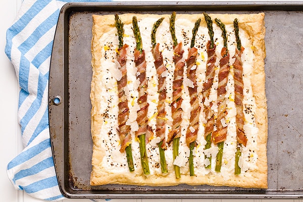 Bacon Wrapped Asparagus Puff Pastry Tart with a Parmesan ricotta cheese filling is a delicate, flakey appetizer to celebrate spring and Easter. Serve it for brunch or dinner.