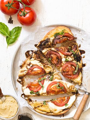 Looking for something quick and fresh to eat? Try this Caprese Hummus Flatbread Pizza with fresh tomatoes, sliced mozzarella cheese, basil, and balsamic vinegar.