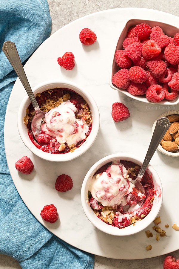 Enjoy a sweet ending to your day with mini Raspberry Almond Crisp For Two with a sweet and slightly tart raspberry filling topped with a crispy almond streusel baked in two ramekins.