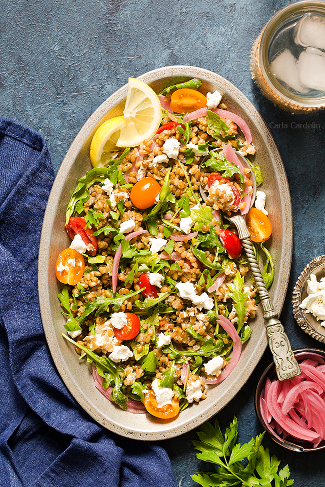 A hearty whole grain salad with freekeh, arugula, tomatoes, goat cheese, and pickled red onion.