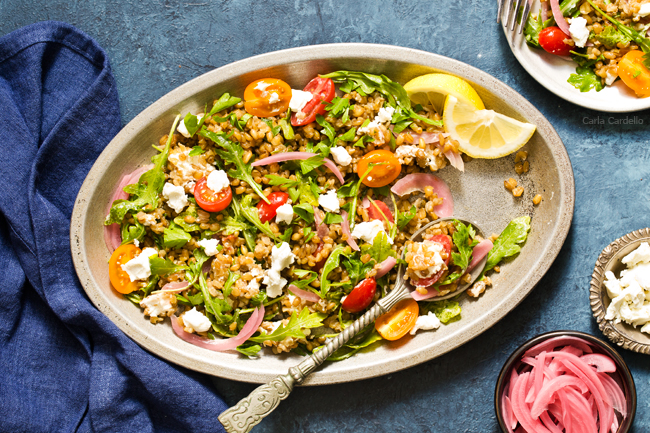 A hearty whole grain salad with freekeh, arugula, tomatoes, goat cheese, and pickled red onion.