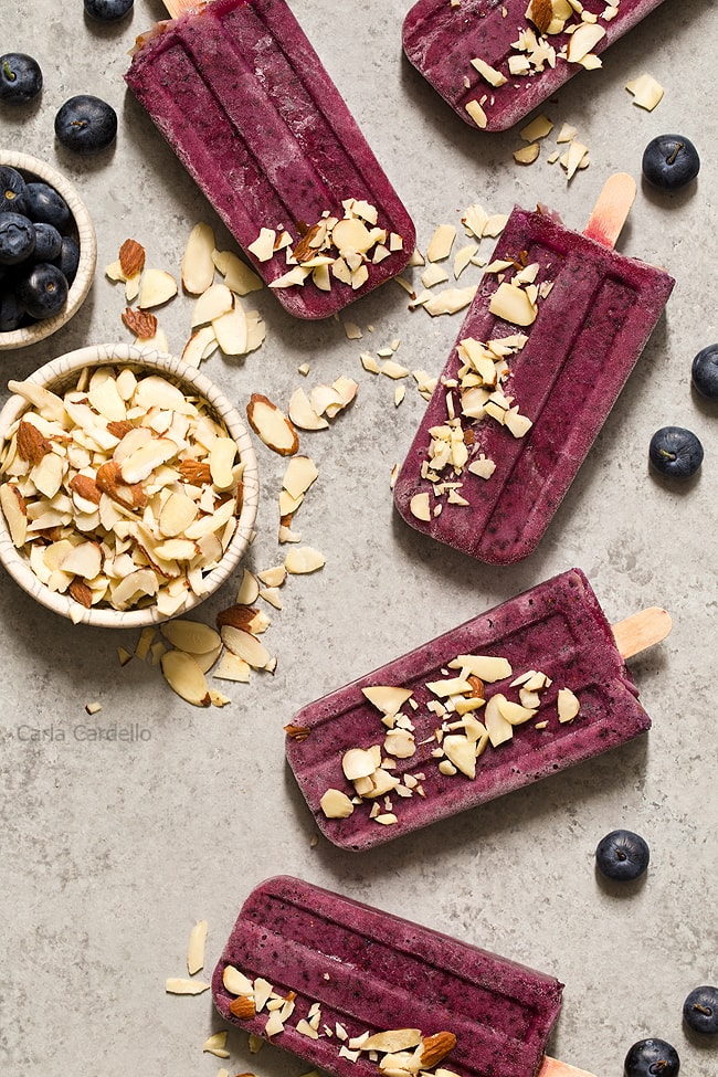 Cool down this summer with something colorful and refreshing! Blueberry Yogurt Popsicles with almonds and a secret ingredient that makes their flavor pop.