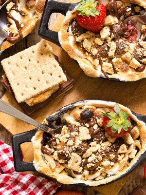 Strawberry S'mores Cobbler with a chocolate strawberry filling topped with toasted marshmallows and graham cracker pieces. Bake them in the oven for a gooey, irresistible smores dessert!