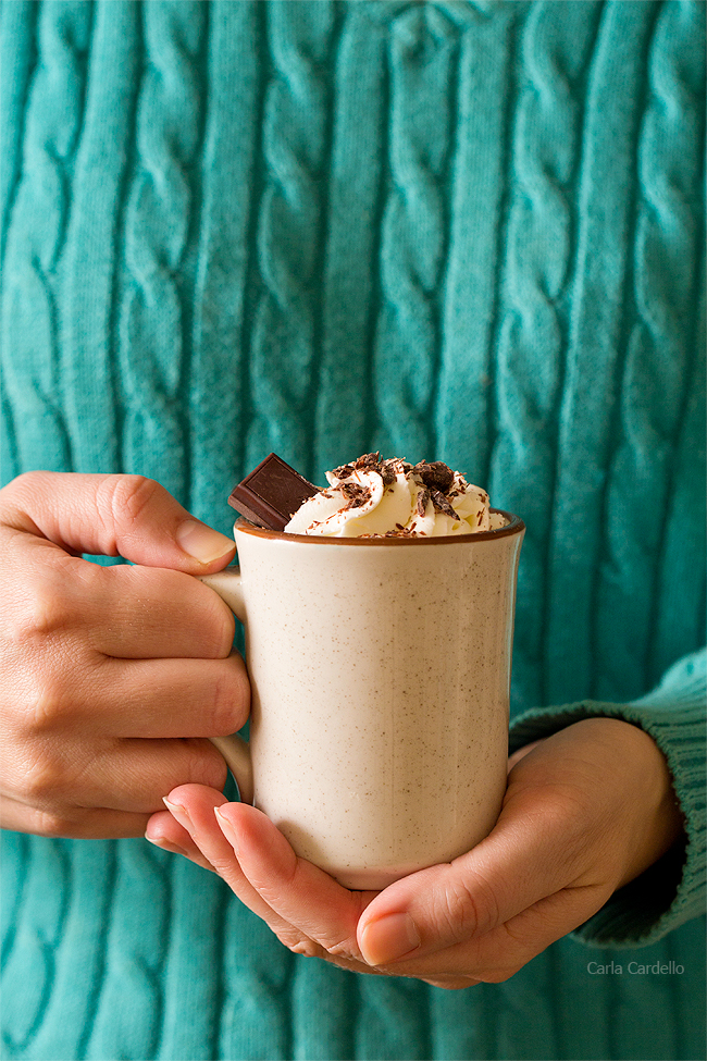 Woman in turquoise sweater holding mug of thick hot chocolate