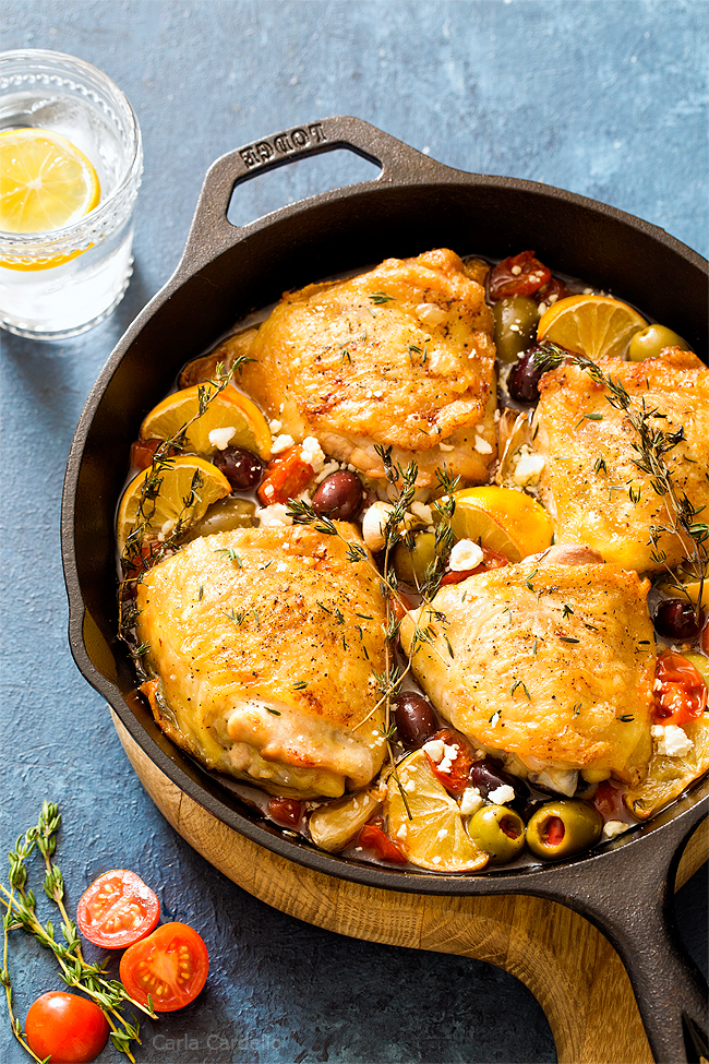 Chicken thighs in cast iron skillet with tomatoes and olives