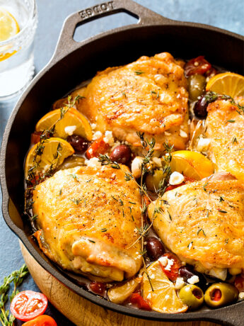 Chicken thighs in cast iron skillet with tomatoes and olives
