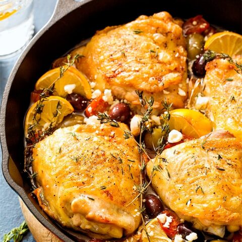 Chicken thighs in cast iron skillet with tomatoes and olives