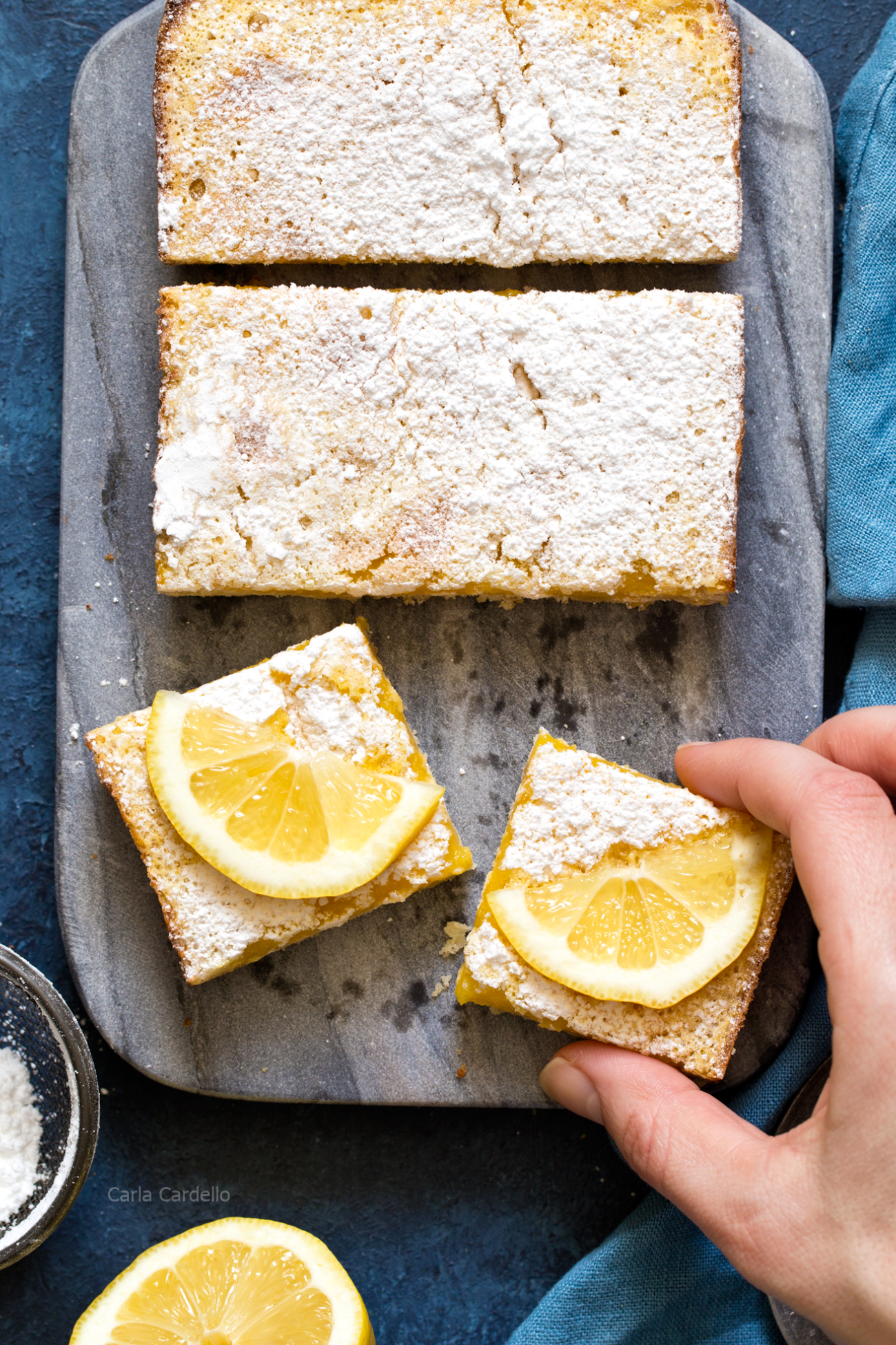 Hand grabbing Small Batch Lemon Bars made in a loaf pan