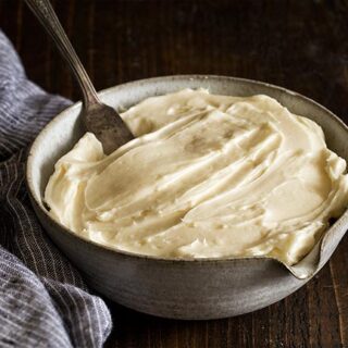 Homemade Cream Cheese Frosting in a bowl with wooden spoon