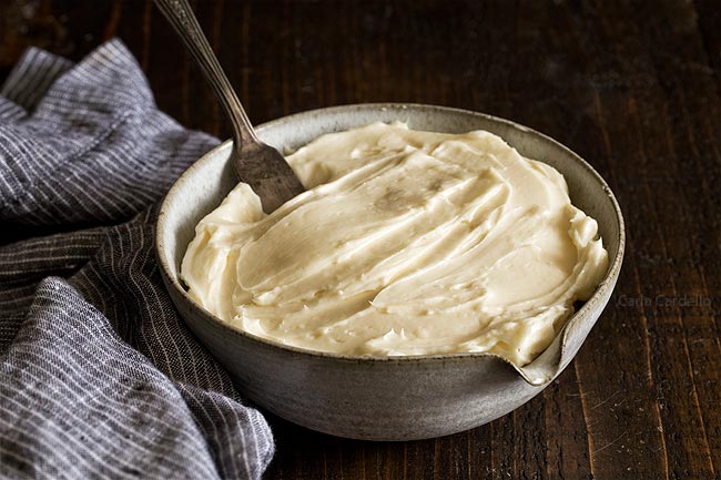 Homemade Cream Cheese Frosting in a bowl with wooden spoon