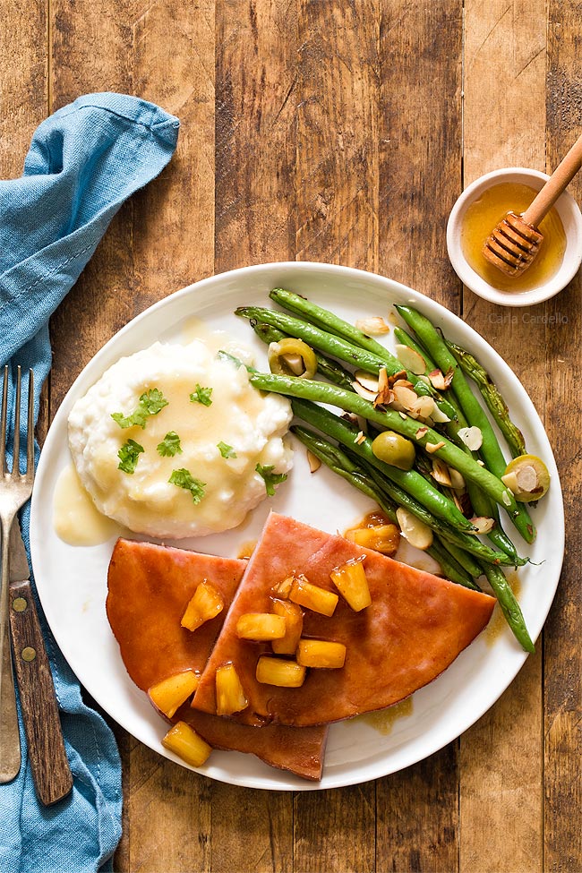 Honey Glazed Ham Steak on white plate with green beans and mashed potatoes