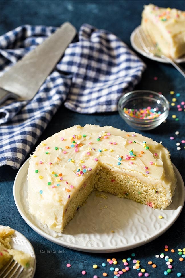 Wide shot of small birthday cake on white serving platter