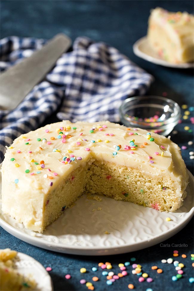 Small birthday cake with slices cut on a white plate