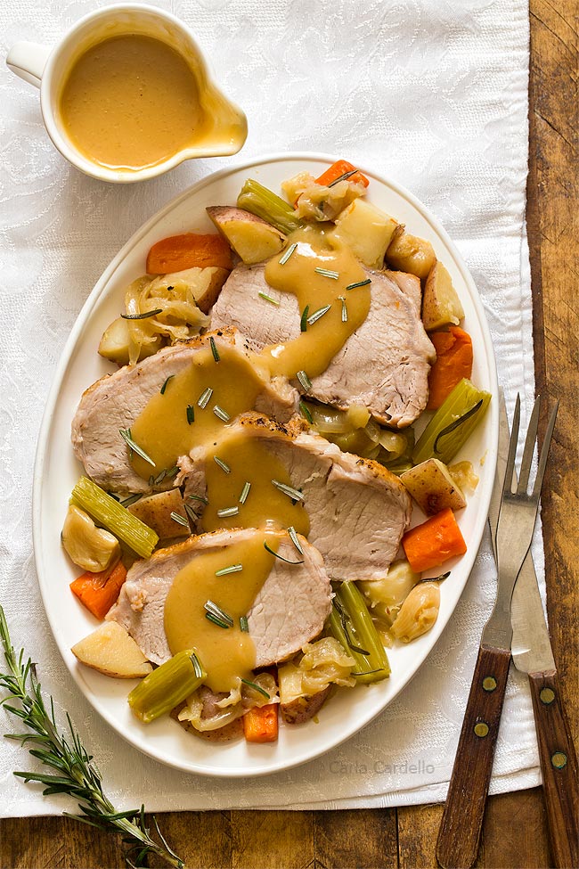 Pork roast on white plate with gravy and vegetables