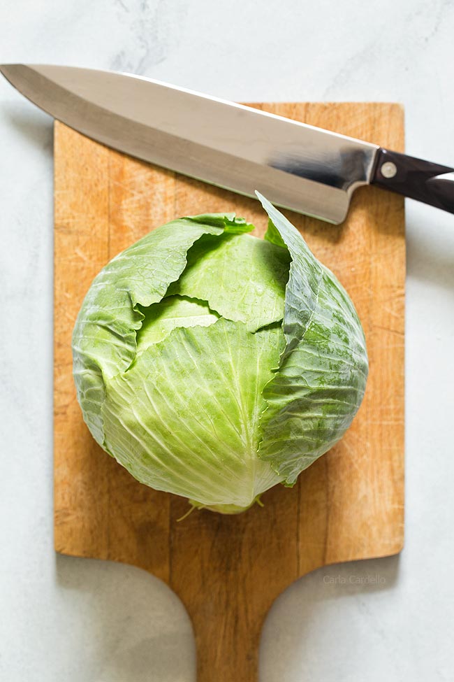 Whole cabbage on cutting board with knife